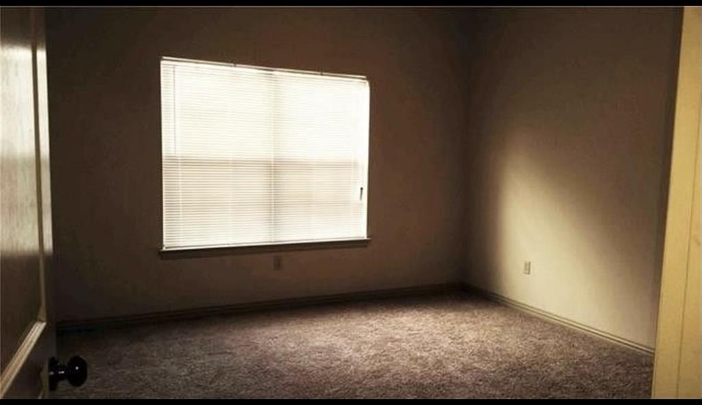 Room featuring a window with horizontal blinds and textured carpeting