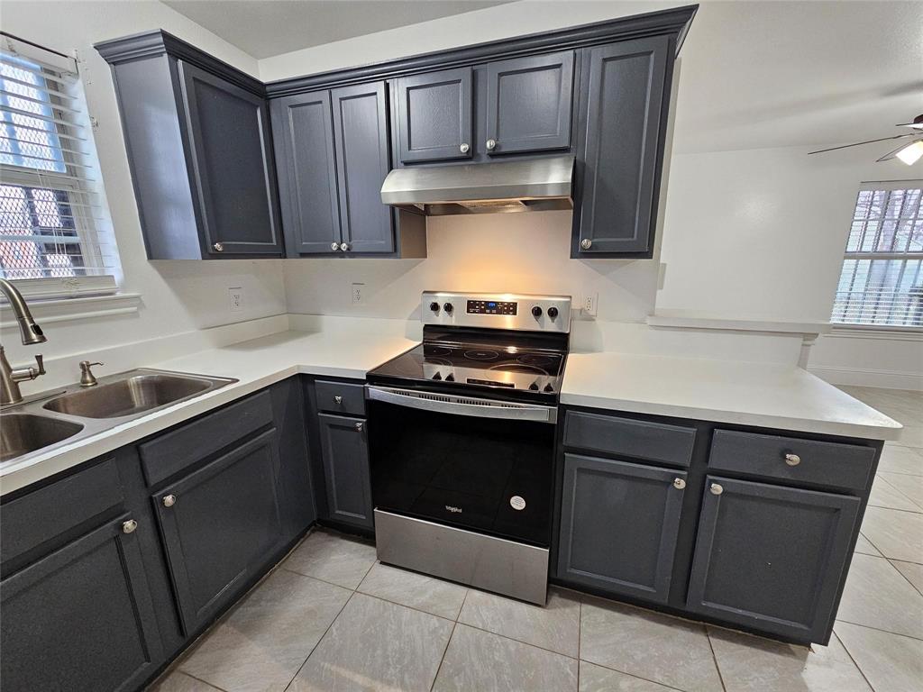 Kitchen featuring dark cabinetry, light countertops, stainless steel appliances, and a dual basin sink