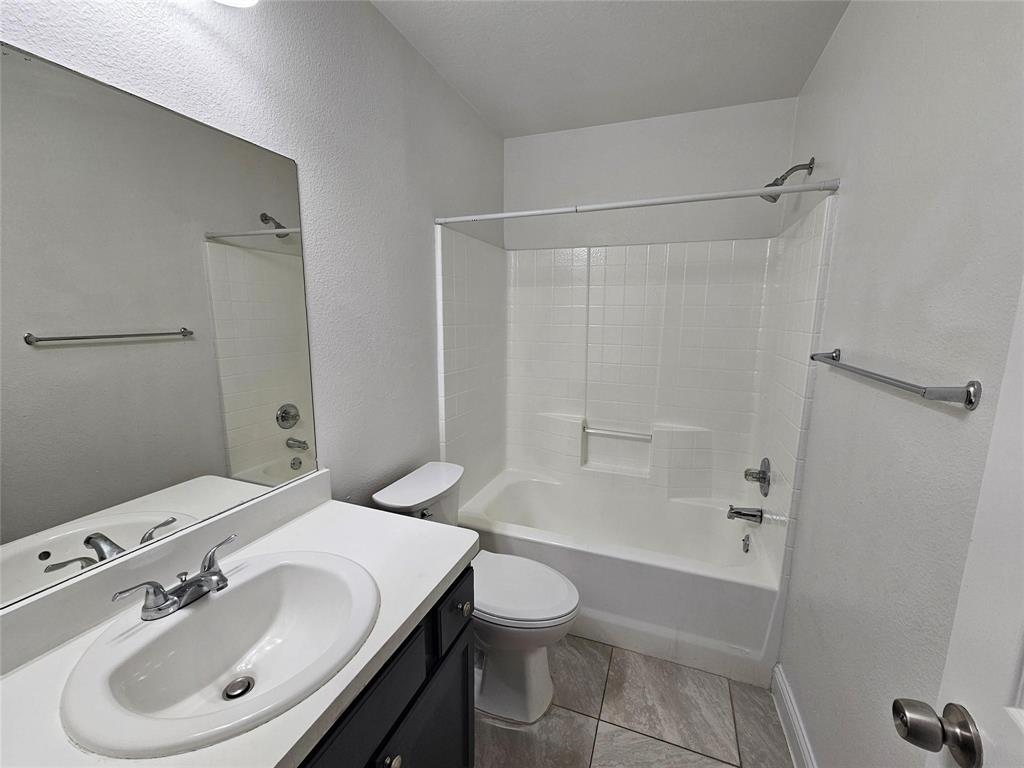 Bathroom with a vanity, oval sink, and a combination tub and shower with white tile surround