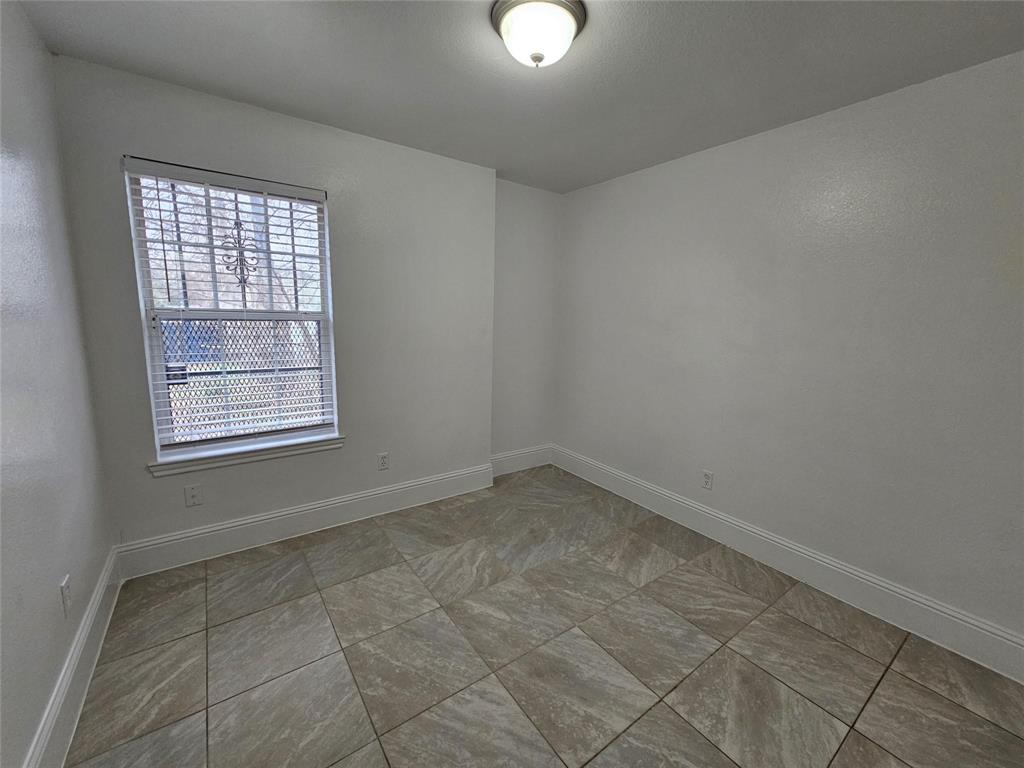 Neutral wall color with textured finish, tiled flooring, window with horizontal blinds, and a ceiling-mounted light fixture
