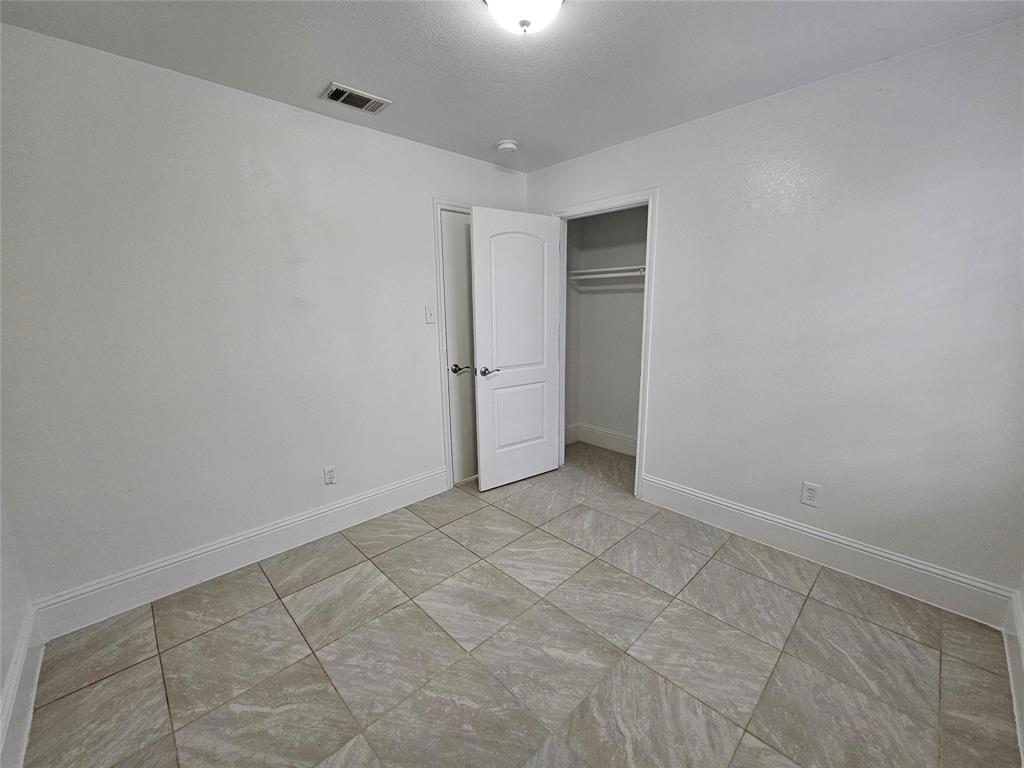 Neutral white wall finish, recessed lighting, tile flooring, interior door with polished hardware, and an integrated closet with hanging rod