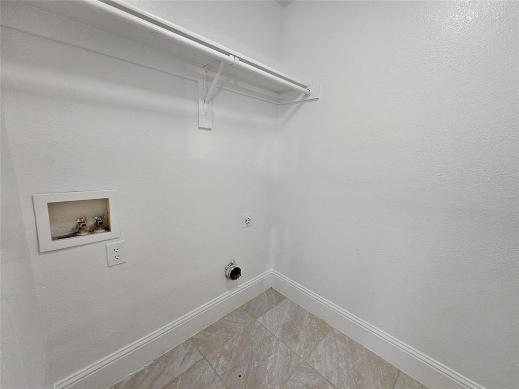 Laundry utility area with tile flooring and a wall-mounted clothing rod
