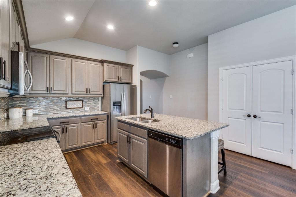 Kitchen featuring wood-finish flooring, recessed lighting, a kitchen island with sink, and white paneled double doors