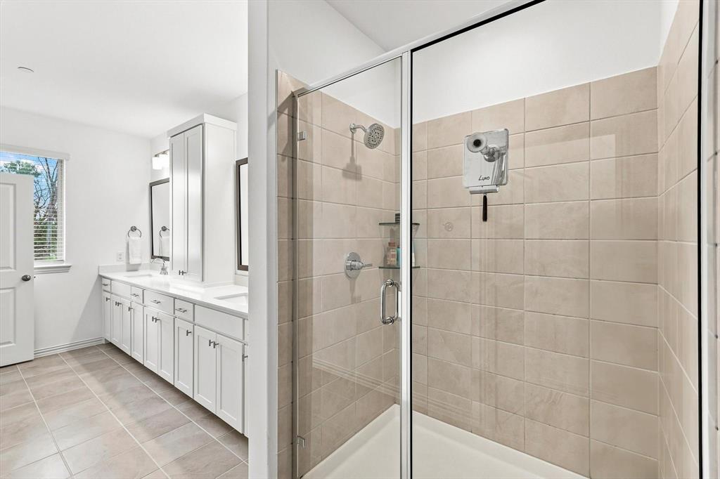 A relaxing finish to the primary suite. The spacious glass-enclosed shower features neutral tile and a clean, timeless design.
