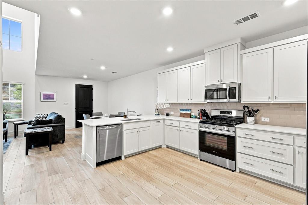 Bright, polished, and effortlessly inviting. Crisp white cabinetry, stainless appliances, generous prep space, and seamless flow into the living area make this kitchen a standout.