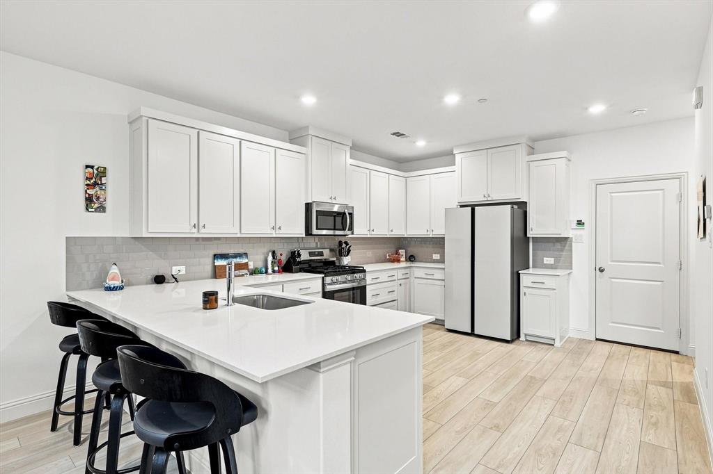Bright, sleek, and made for gathering. The kitchen features crisp white cabinetry, stainless appliances, and an expansive island that anchors the heart of the home.
