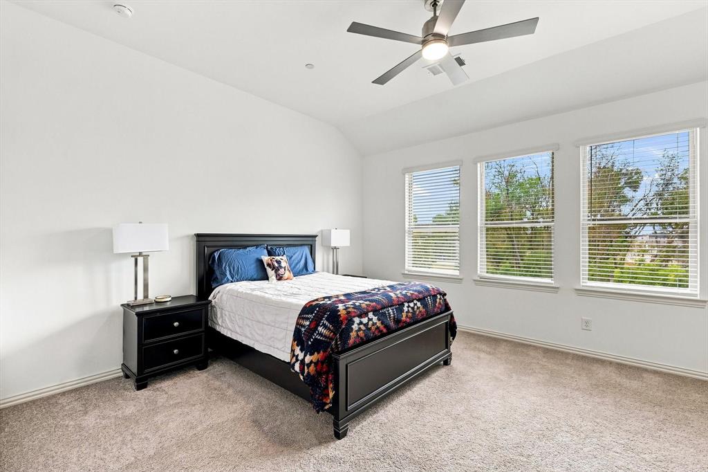 Your private retreat awaits. A spacious primary suite with a vaulted ceiling, ceiling fan, and a wall of windows creates a bright and relaxing escape.