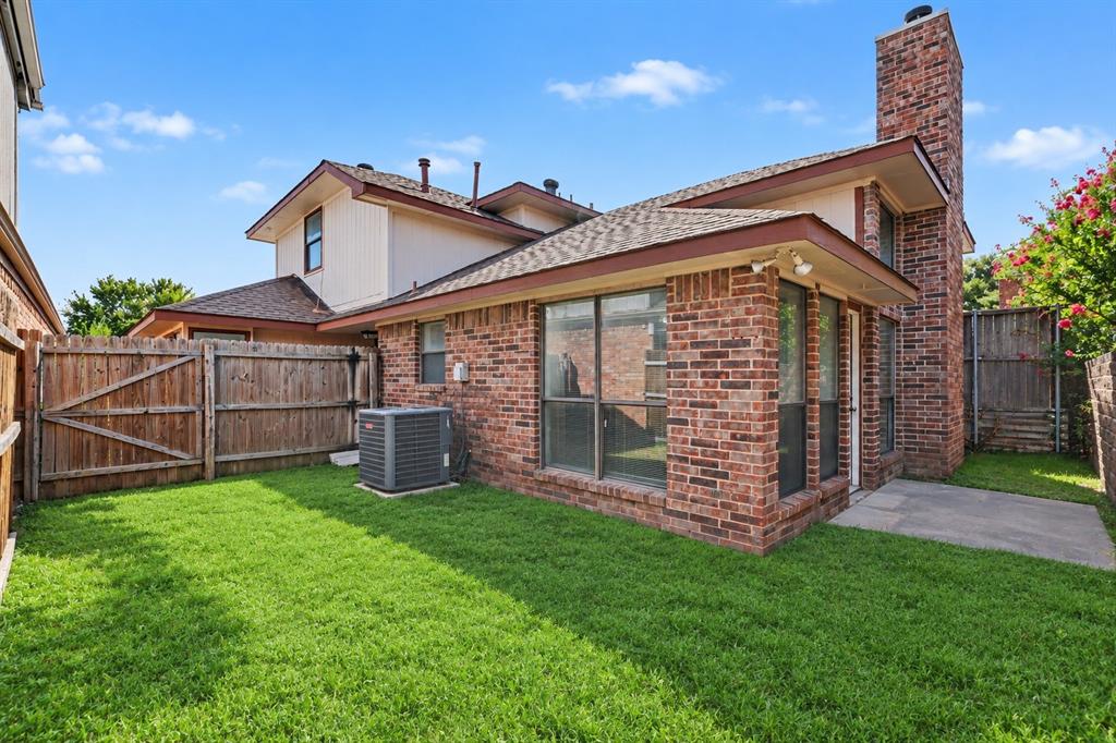 Expansive backyard featuring a meticulously manicured lawn, mature landscaping, and wooden privacy fencing