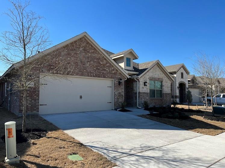 Brick and stone exterior with dormer window accents, attached garage, and concrete driveway