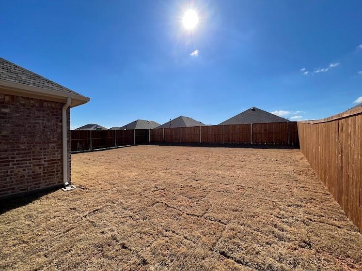 Expansive backyard with a full privacy fence and brick exterior