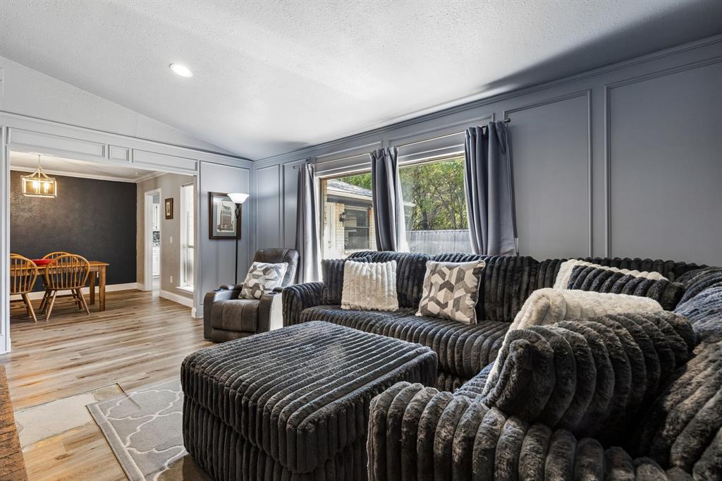 Wood-finish flooring throughout, vaulted ceiling, recessed lighting, and decorative wall paneling