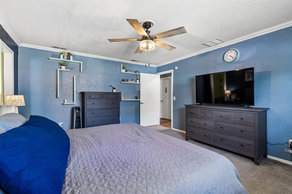 Ceiling fan with integrated lighting, textured walls, permanent shelving, crown molding, and an interior door