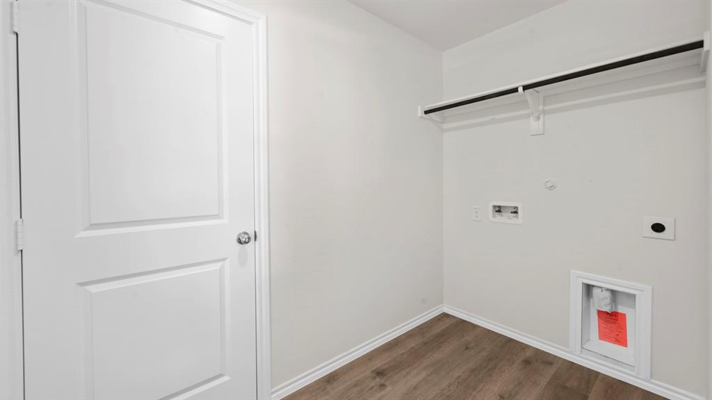 Utility space featuring wood-finish flooring, a clothing rod, and essential appliance hook-ups