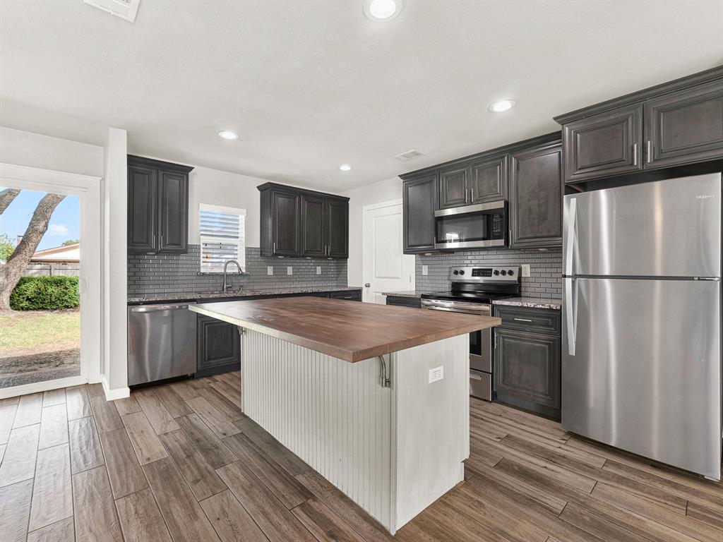Plenty of storage space, granite counters, butcher block island, and a modern backsplash