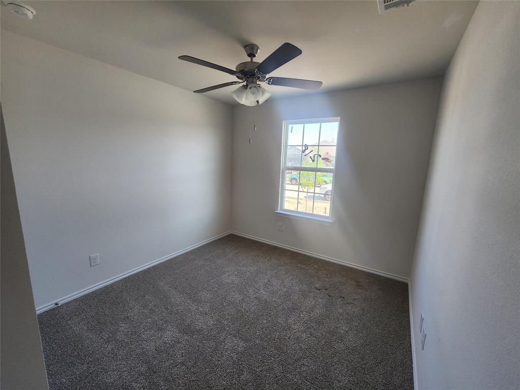 Carpeted flooring with a ceiling fan and a window