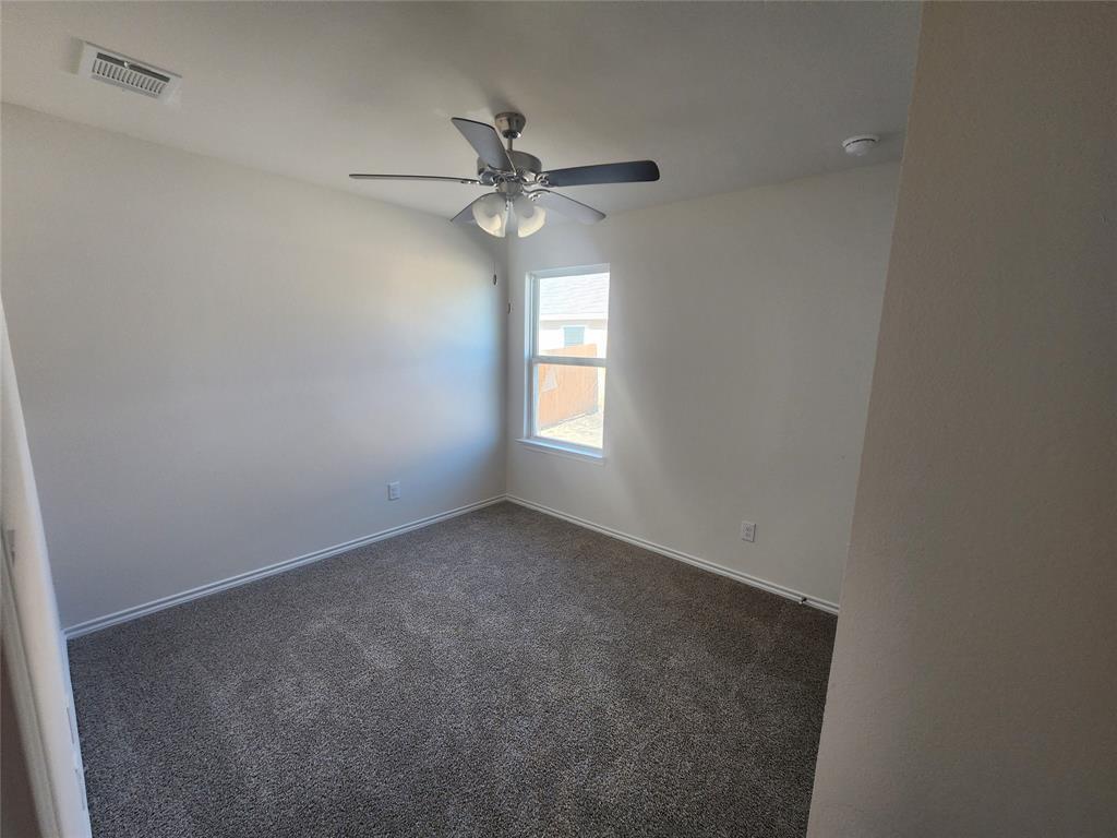 Neutral wall paint, ceiling fan with light fixture, window with white frame, and gray carpet flooring