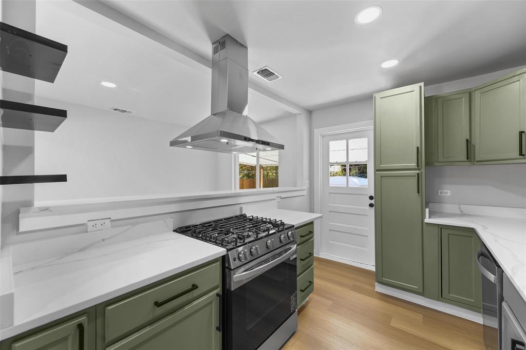 Kitchen featuring sage green cabinetry, stainless steel range with overhead hood, white countertops, wood-finish flooring, and recessed lighting Kitchen featuring sage green cabinetry, stainless steel range with overhead hood, white countertops, wood-finish flooring, and recessed lighting