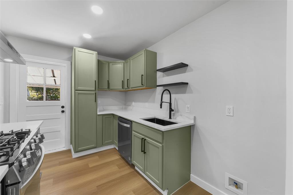 Kitchen featuring light wood-finish flooring, recessed lighting, sage green cabinetry with black hardware, white countertops, and a black sink with a matte black faucet Kitchen featuring light wood-finish flooring, recessed lighting, sage green cabinetry with black hardware, white countertops, and a black sink with a matte black faucet