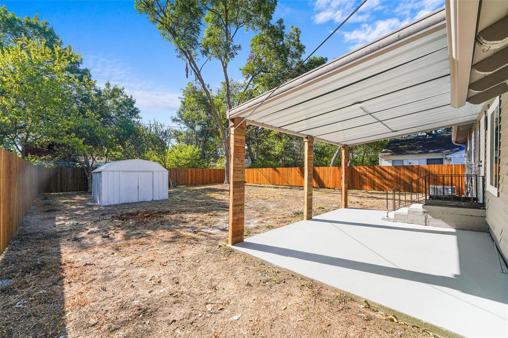 Expansive backyard featuring a privacy fence, covered concrete patio, and detached storage shed
