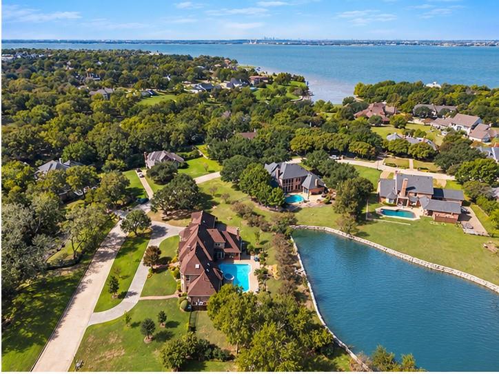 Aerial perspective of a sprawling residential lot featuring a private waterfront pond, an in-ground swimming pool, manicured grounds, and mature tree coverage