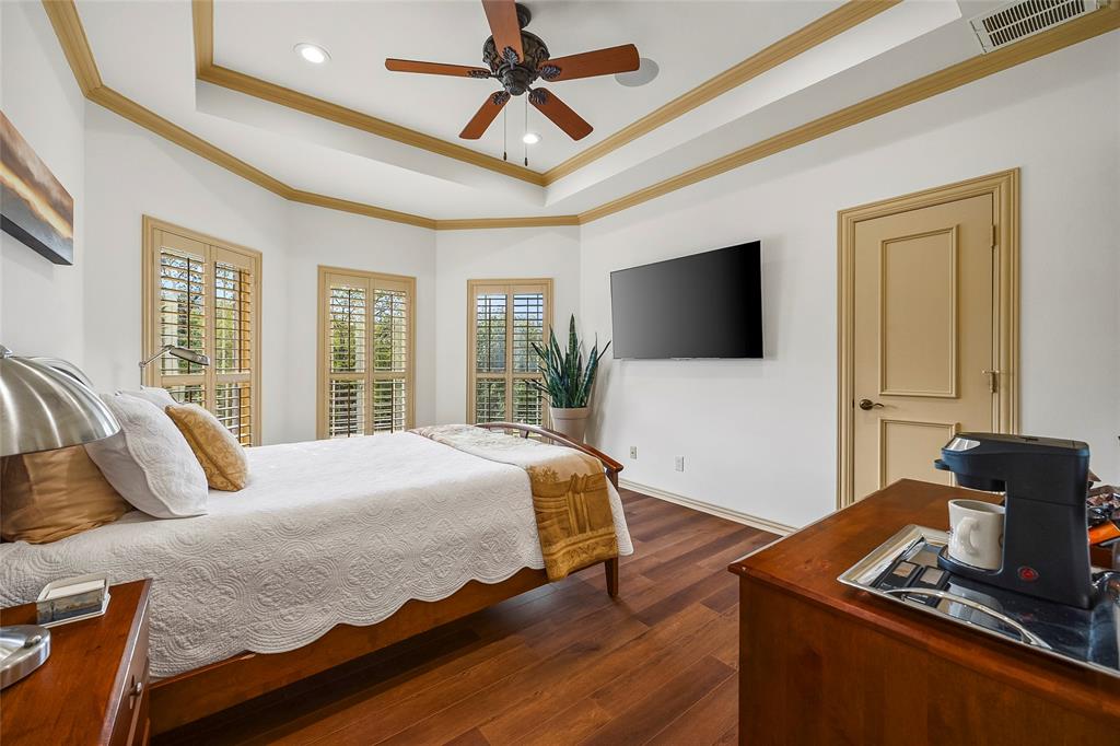 Inviting bedroom featuring a tray ceiling, wood flooring, and ample natural light.