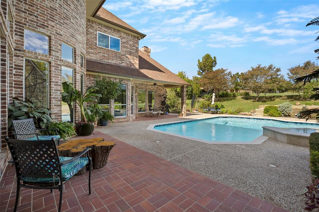 Tranquil covered outdoor living area overlooking the pool and landscaped backyard.