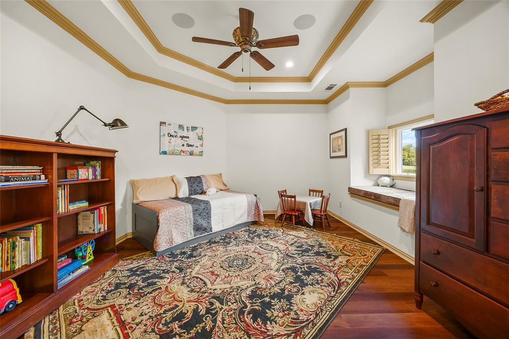 Beautifully appointed bedroom with tray ceiling and warm wood finishes.