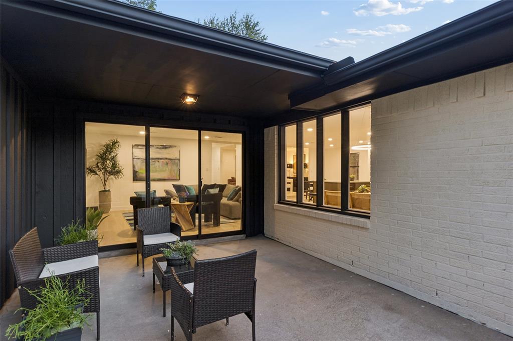 Concrete patio with a dark overhang, white painted brick exterior, and large sliding glass doors