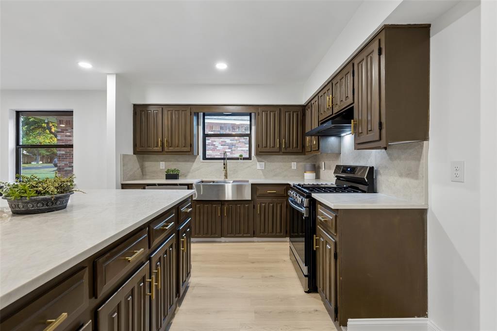 Kitchen with wood-finish cabinetry, light-toned countertops, stainless steel sink, and light wood-finish flooring