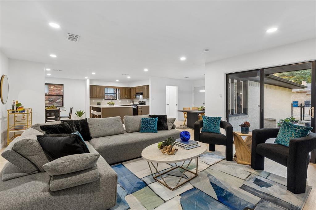 Open-concept living area featuring light wood-finish flooring, recessed lighting, and sliding glass doors
