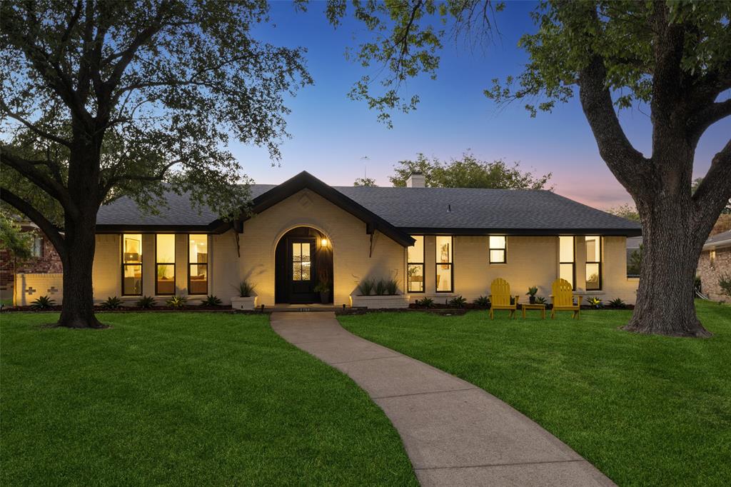 exterior with a dark shingle roof, arched entry, black-framed windows, and a concrete pathway