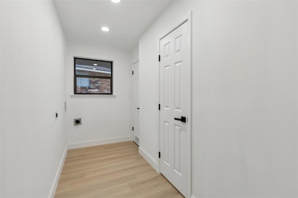 Utility space featuring light wood-finish flooring, recessed lighting, and a window with dark trim