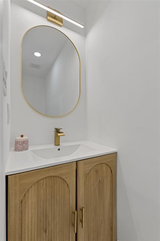 Wood-finish vanity with arched details, gold-finish hardware, and a white countertop with an integrated sink