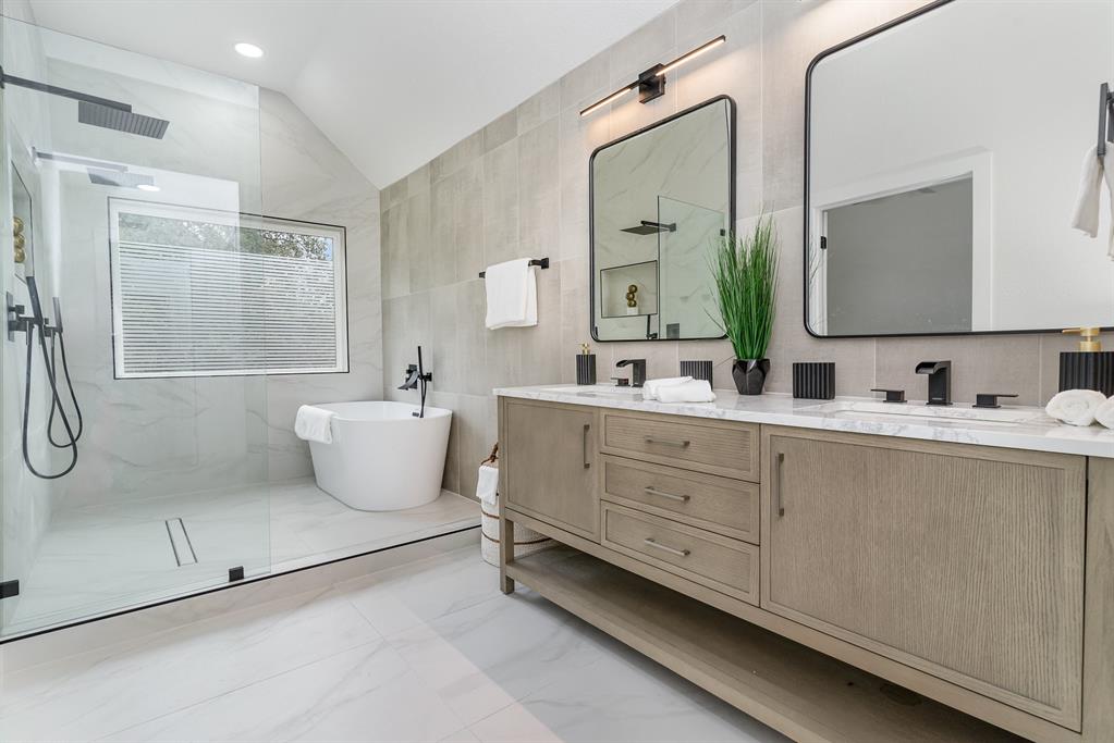 Bathroom with tile walls, vanity, plus walk in shower, and lofted ceiling