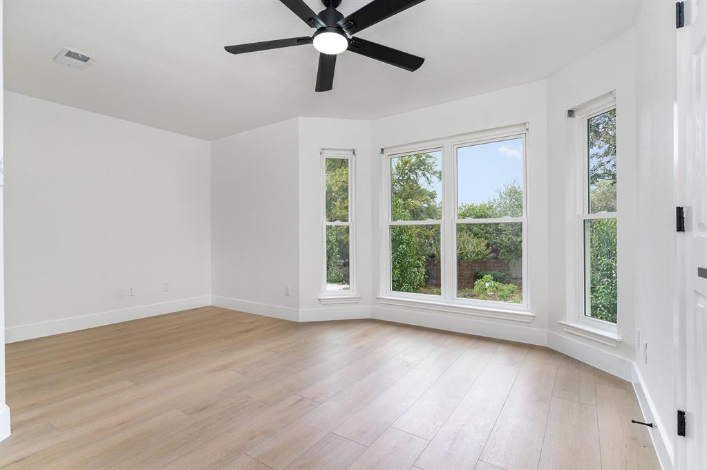 Empty room with a wealth of natural light, light hardwood / wood-style floors, and ceiling fan