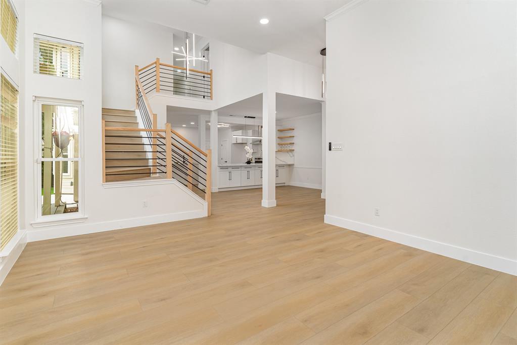 Unfurnished living room with a wealth of natural light, a high ceiling, and light wood-type flooring