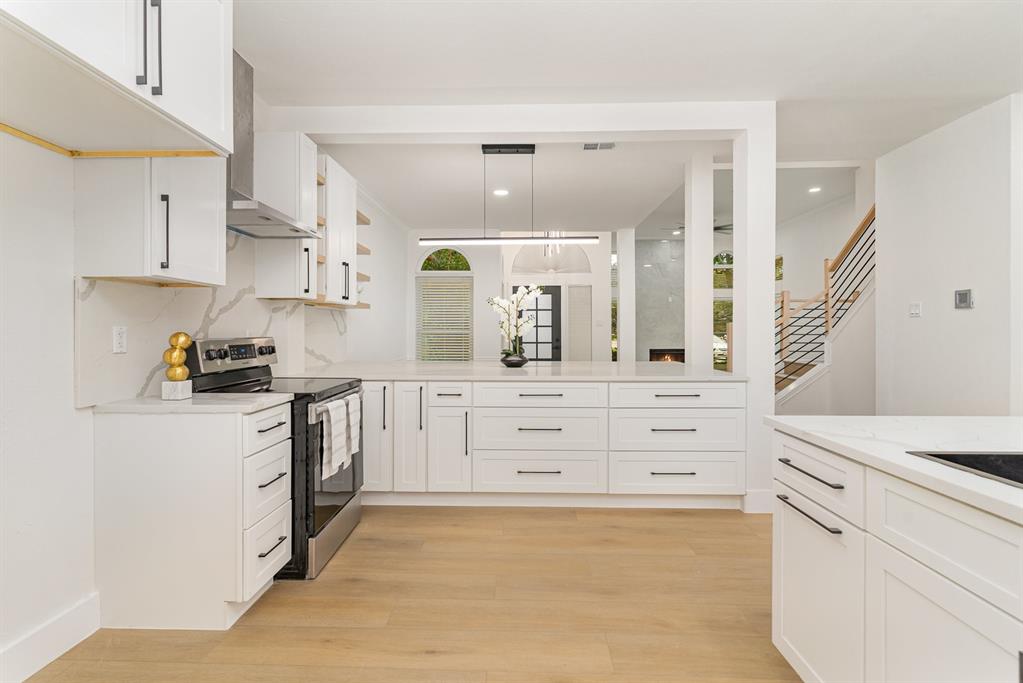 Kitchen featuring pendant lighting, light wood-type flooring, white cabinetry, and stainless steel electric stove