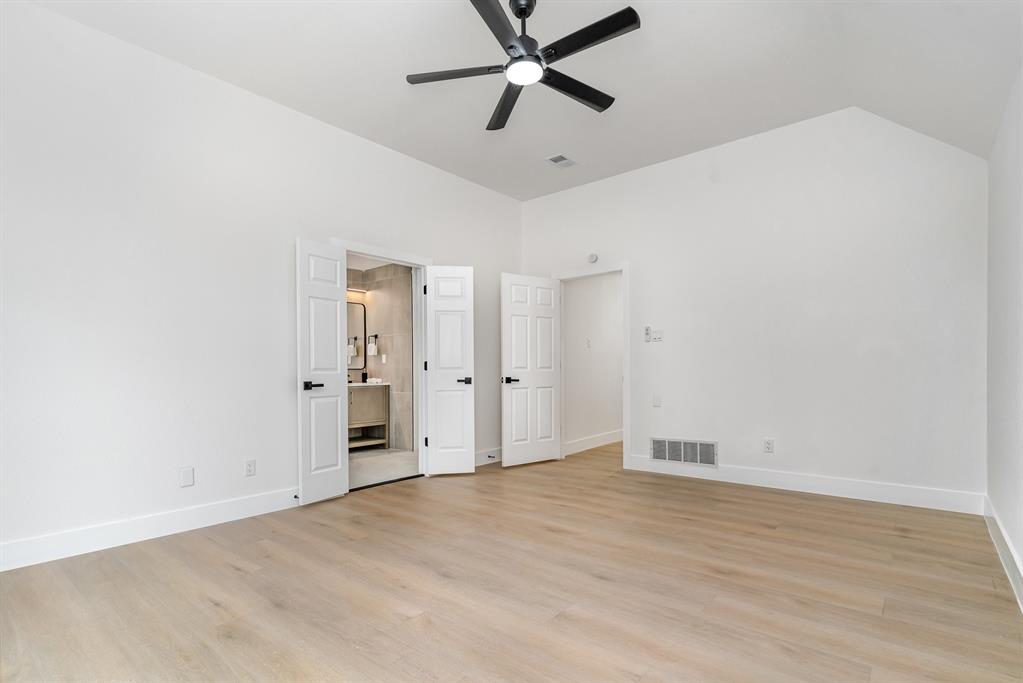 Unfurnished bedroom featuring ensuite bathroom, high vaulted ceiling, light hardwood / wood-style flooring, and ceiling fan