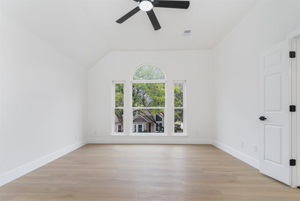 Empty room featuring ceiling fan, lofted ceiling, and light hardwood / wood-style floors