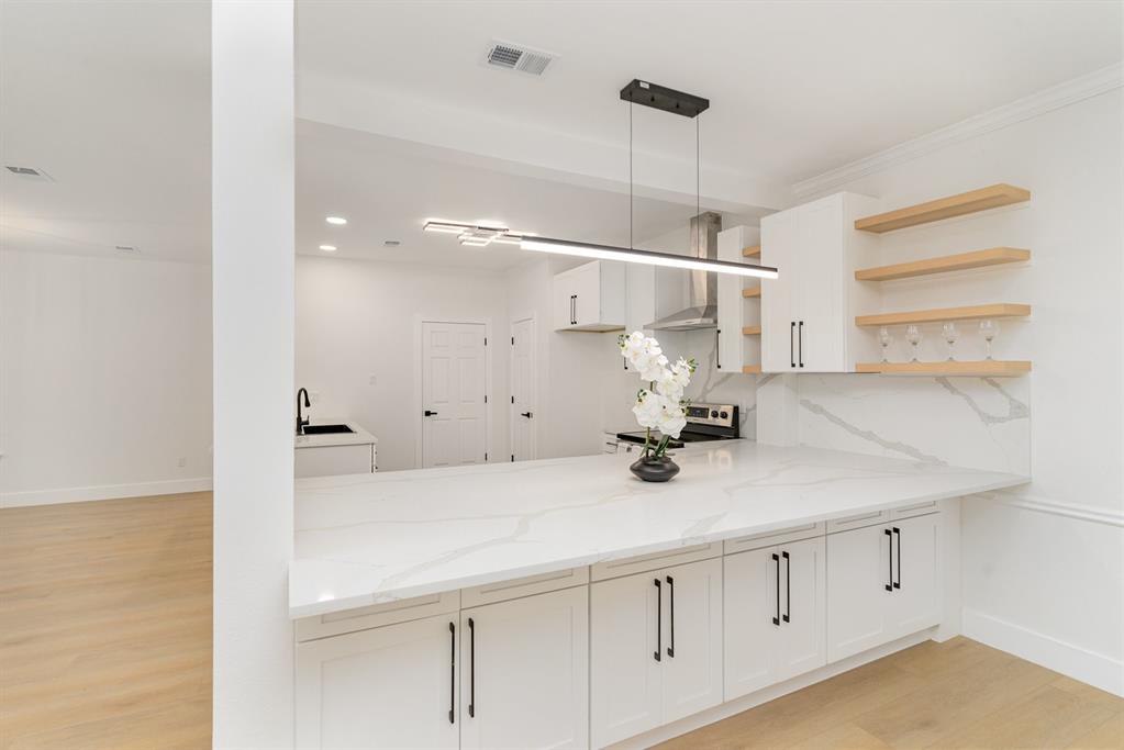 Kitchen with light stone counters, white cabinets, stainless steel electric stove, pendant lighting, and light wood-type flooring