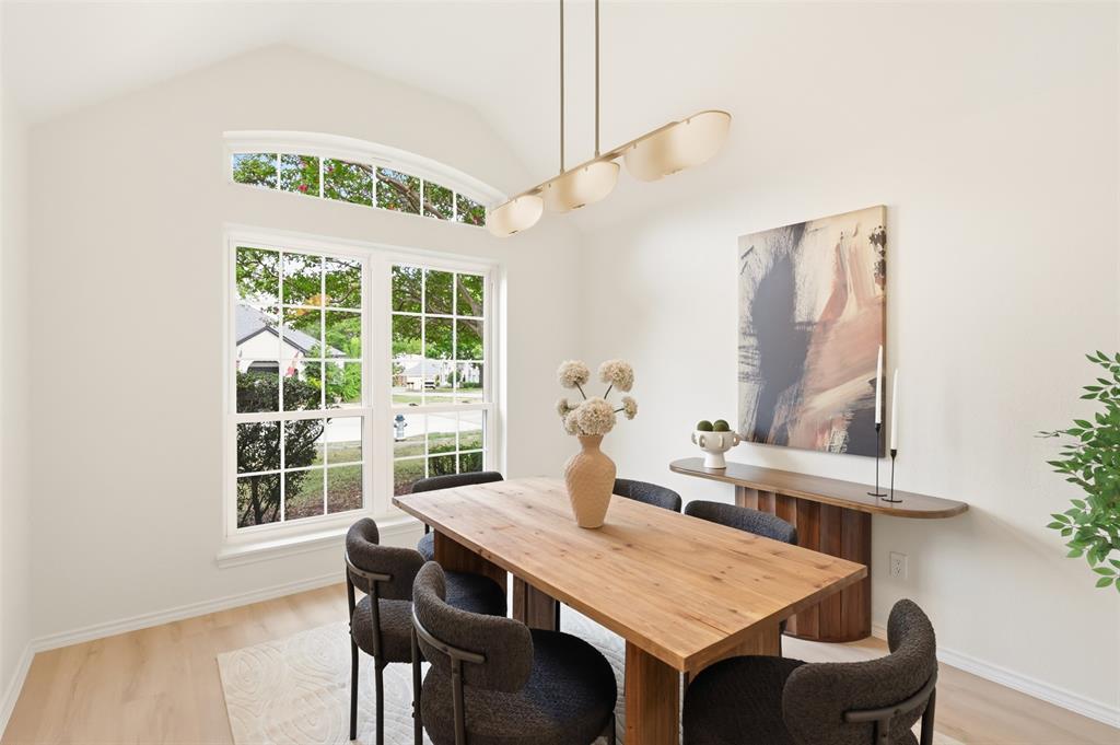 Vaulted ceiling, arched transom window, large grid-patterned window, wood-finish flooring, and a linear pendant light fixture