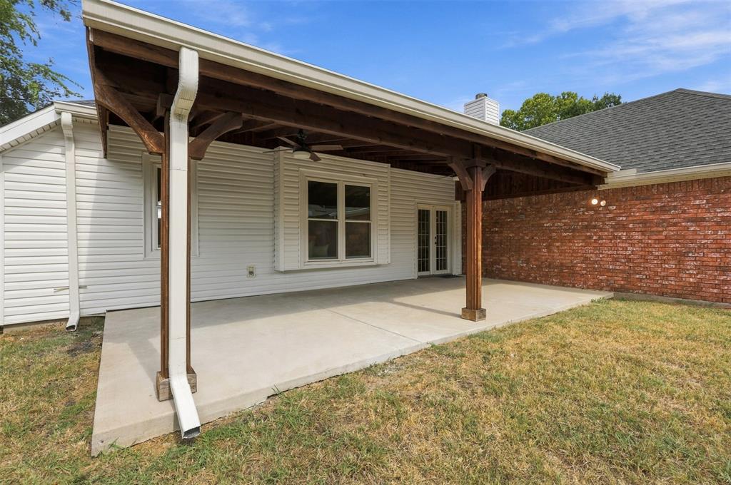 Covered patio with a ceiling fan, concrete flooring, and exposed wood beams