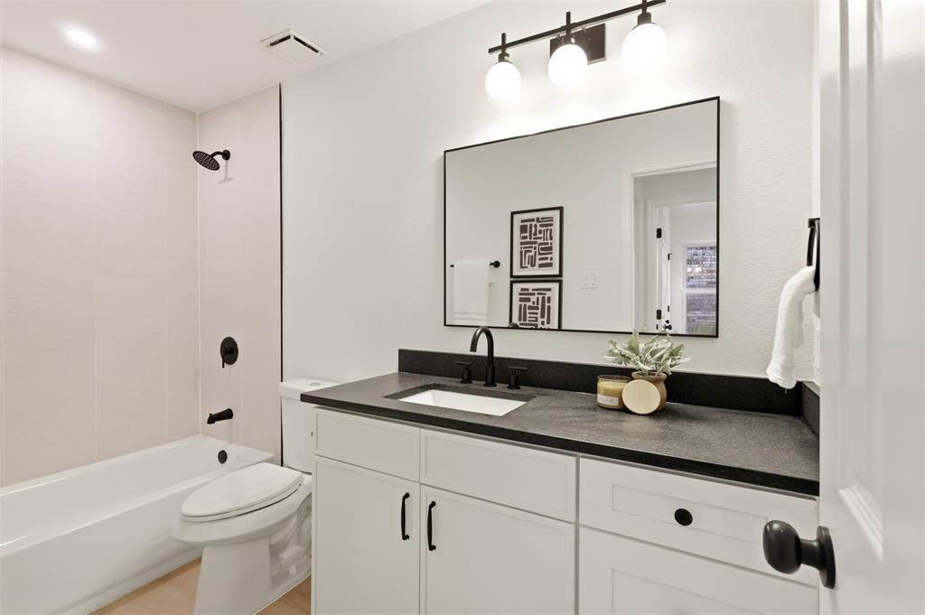 Bathroom featuring white cabinetry, a dark countertop, an undermount sink with a matte black faucet, and a large framed mirror