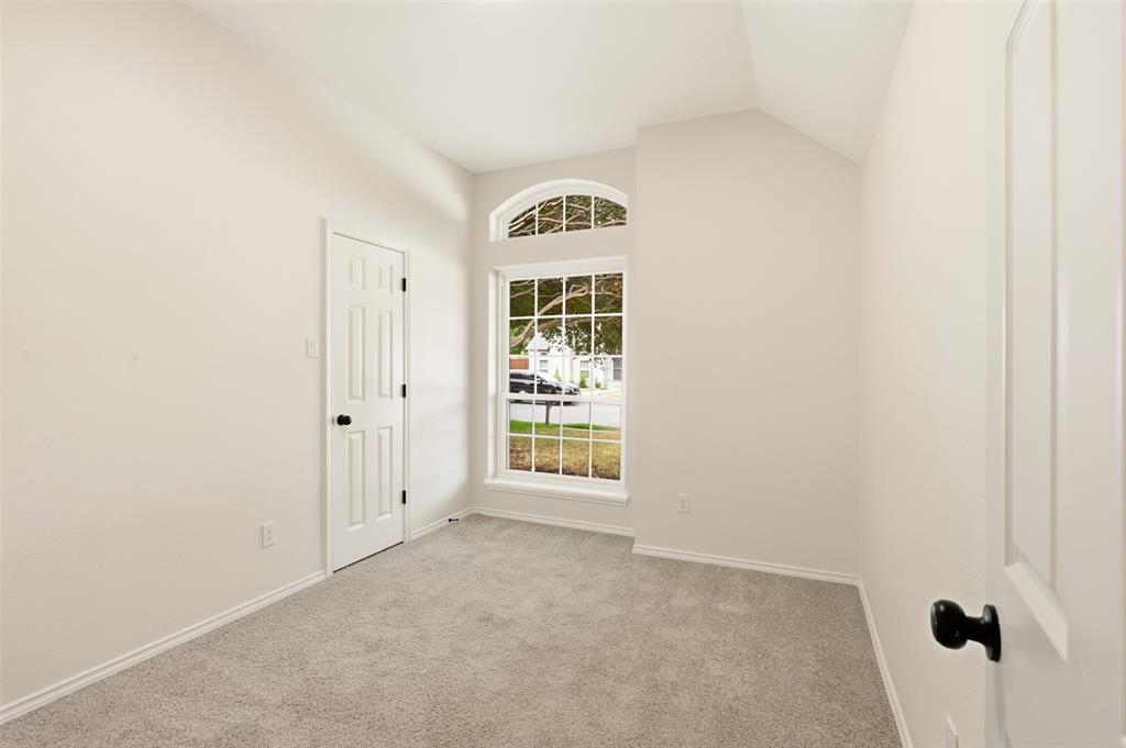 Room featuring vaulted ceiling, arched transom window, paneled doors, and gray carpeting
