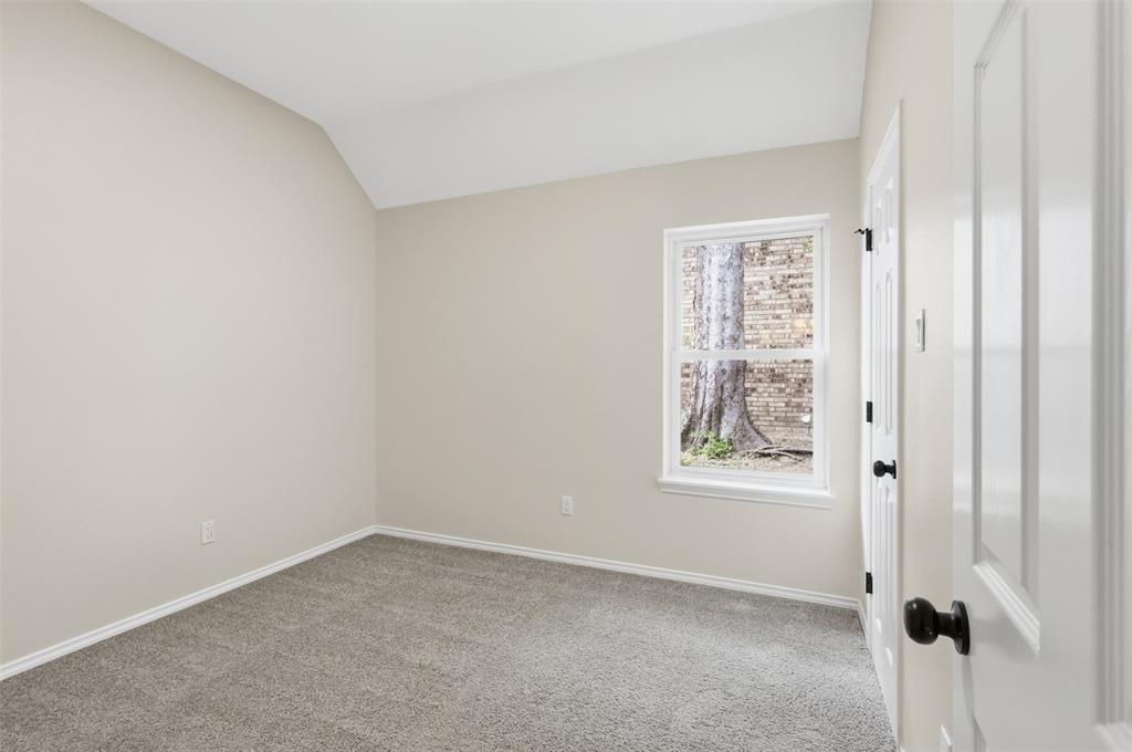Vaulted ceiling, neutral wall paint, gray carpeting, single window, paneled door with black hardware