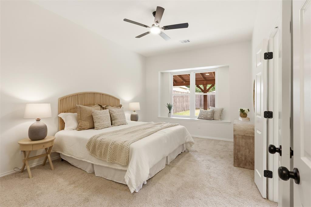 Recessed window alcove, ceiling fan, white paneled door, black door hardware, and light-toned carpet
