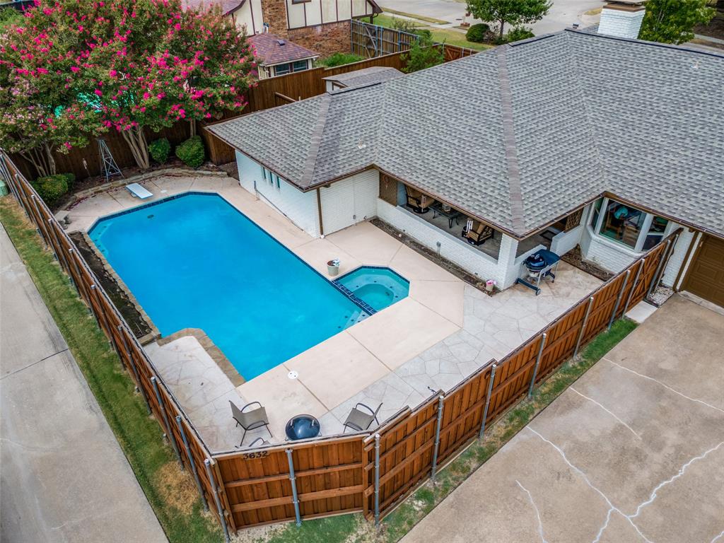 Private backyard featuring a rectangular pool with an attached spa, wood privacy fencing, and stone paver patio