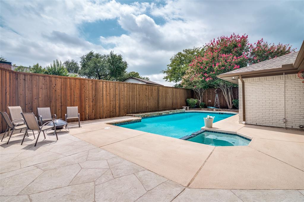 Swimming pool with integrated spa, expansive concrete patio, and privacy fencing