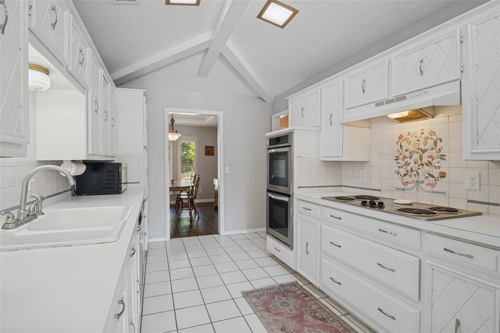 Galley kitchen featuring white cabinetry, tile flooring, built-in double oven, and an electric cooktop