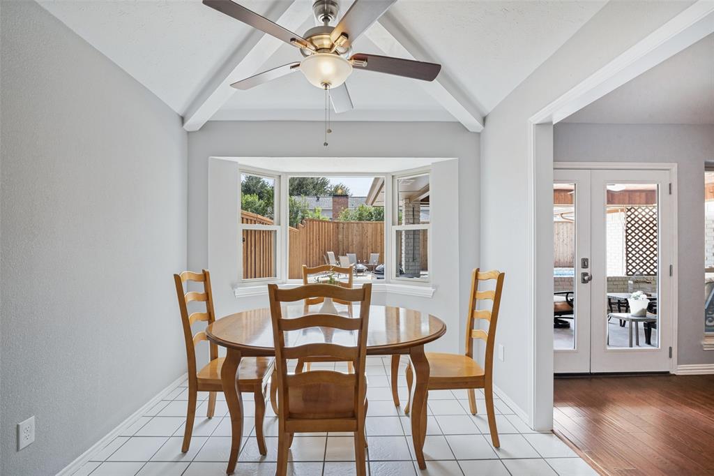 Vaulted ceiling with exposed beams, ceiling fan light fixture, bay window, white tile flooring, and double French doors with glass panels